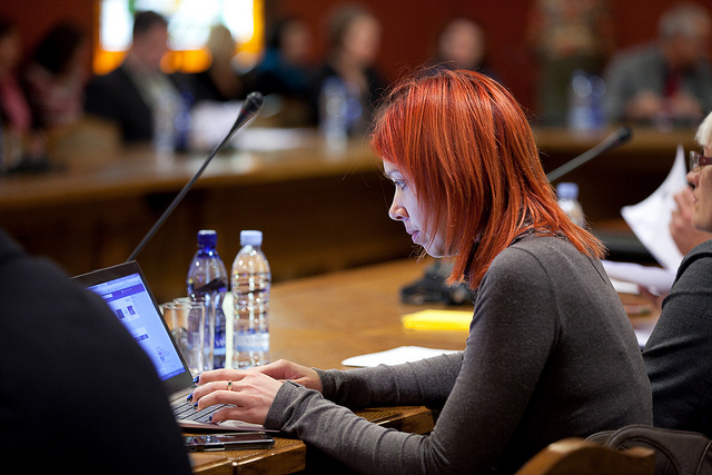 Kristīne ar sarkaniem matiem strādā pie klēpjdatora konferencē